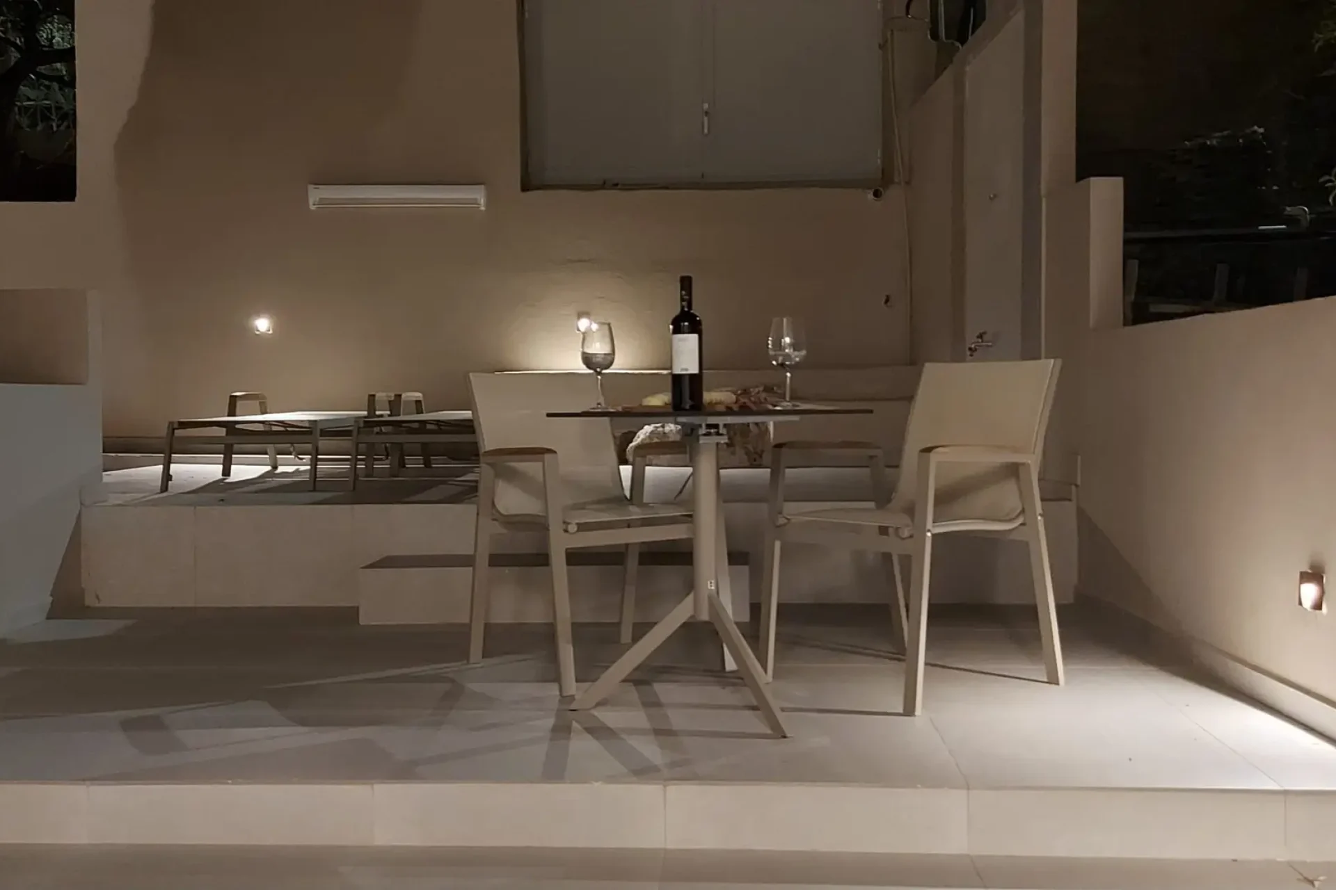 Πίσω αυλή διαμερίσματος Euthea το βράδυ με φωτισμό και ποτήρια κρασί